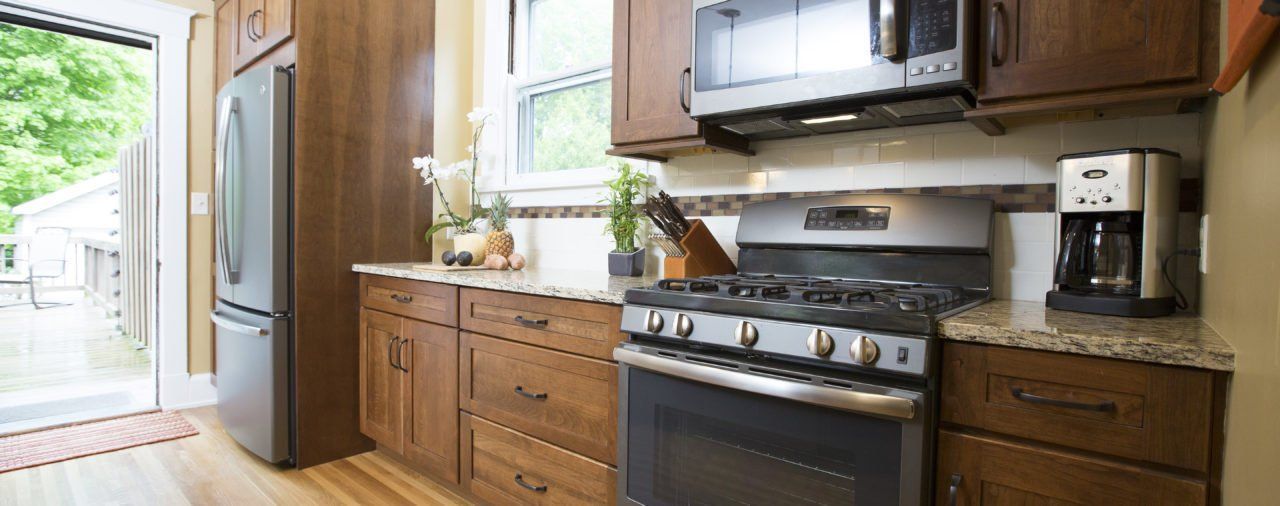 A kitchen with a stove , microwave , refrigerator and coffee maker.