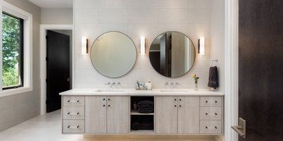 A bathroom with two sinks and two round mirrors.