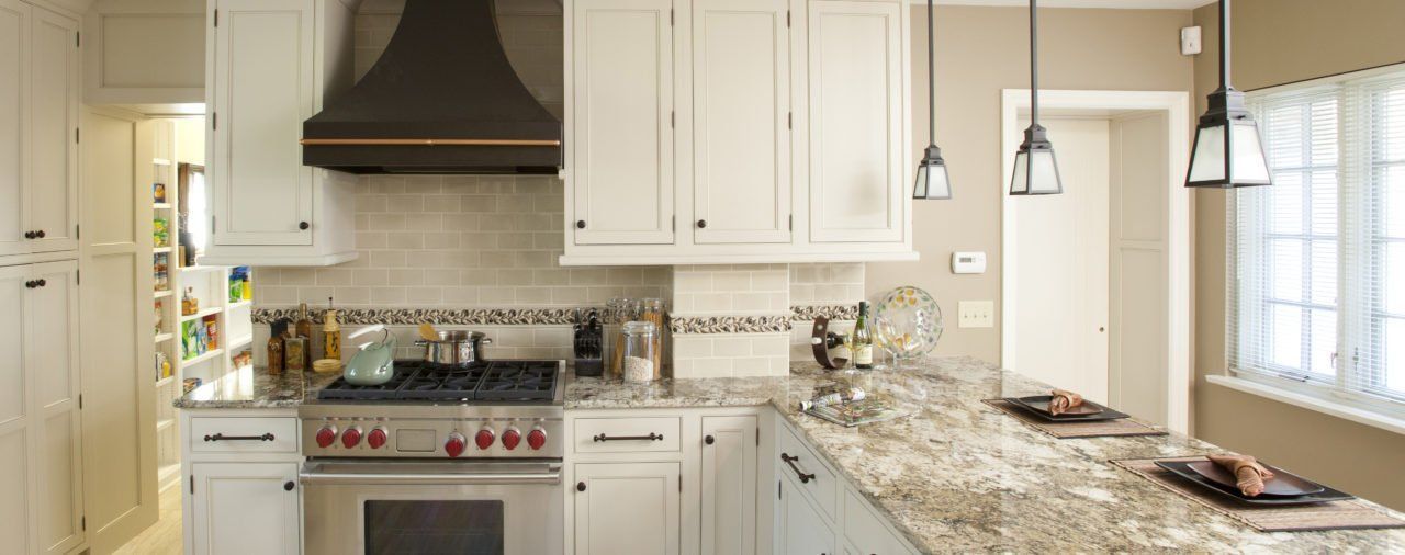 A kitchen with white cabinets , stainless steel appliances and granite counter tops.