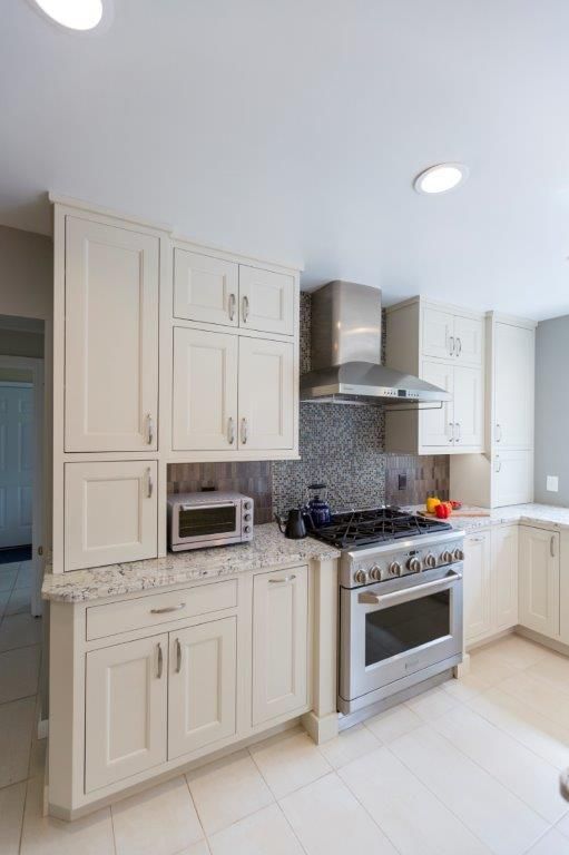 A kitchen with white cabinets , a stove and a microwave.