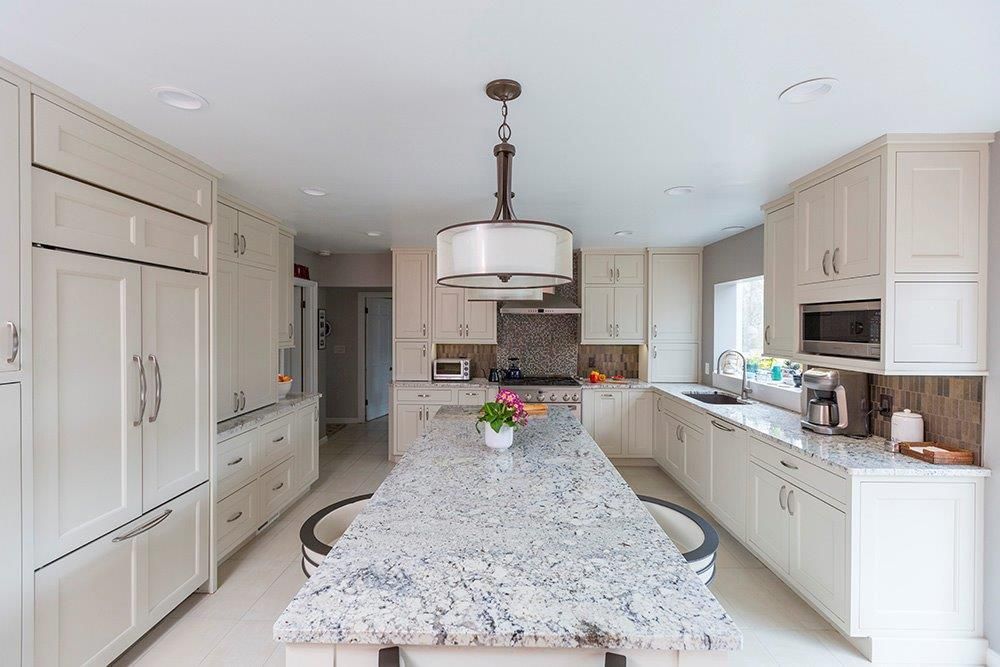 A kitchen with white cabinets and granite counter tops.