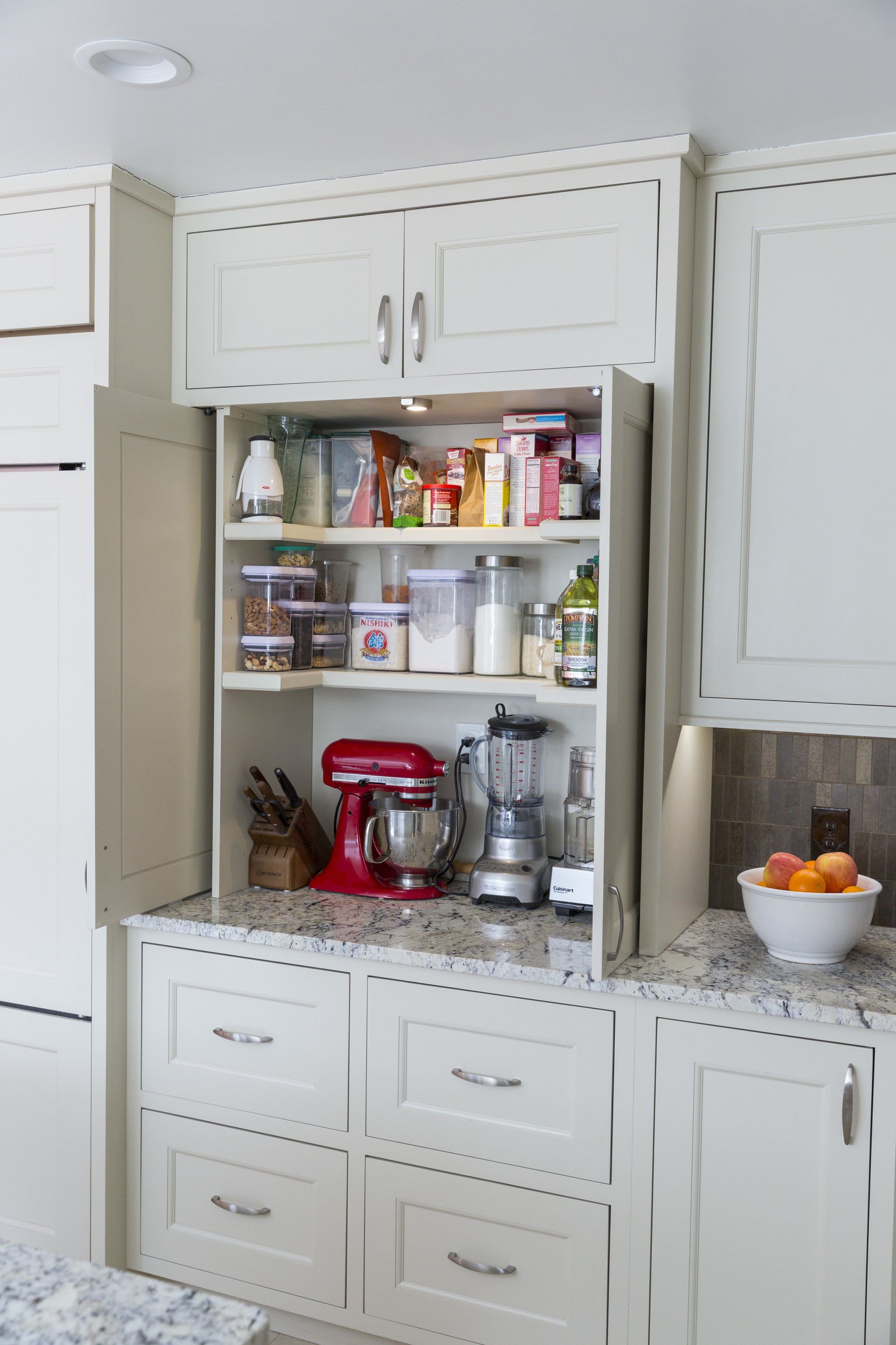 A kitchen with white cabinets and a blender on the counter.