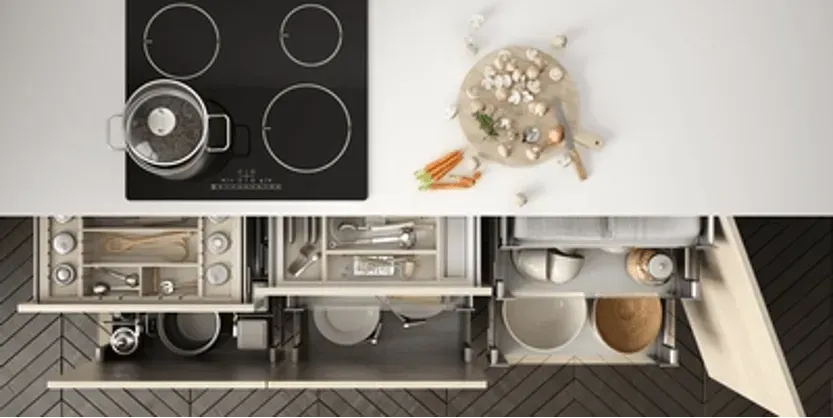 A kitchen with a stove top oven , pots and pans , and drawers.