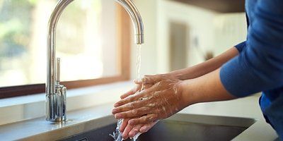 A person is washing their hands in a kitchen sink.