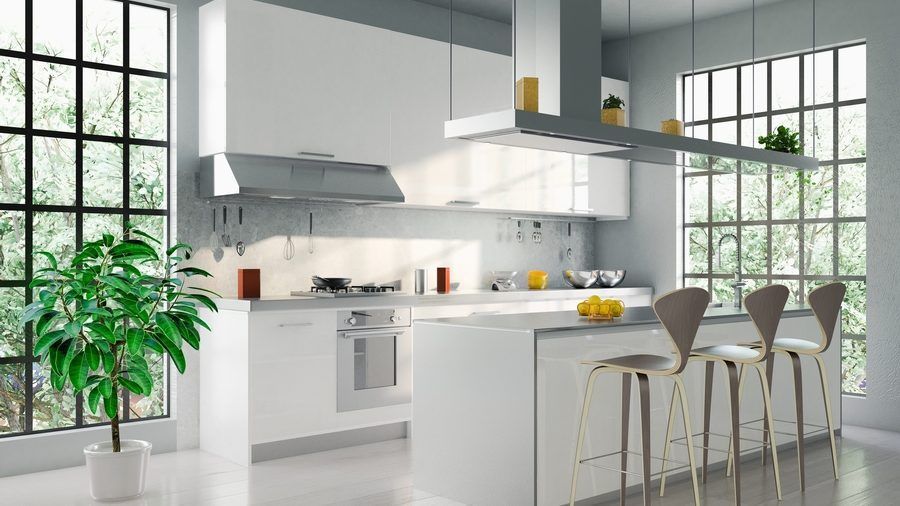 A modern kitchen with white cabinets , stools , and a large island.