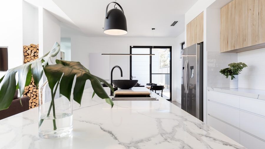 A kitchen with a marble counter top and a vase of flowers on it.