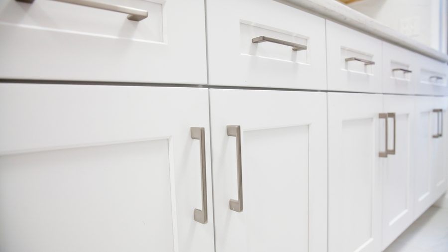 A kitchen with white cabinets and drawers with stainless steel handles.
