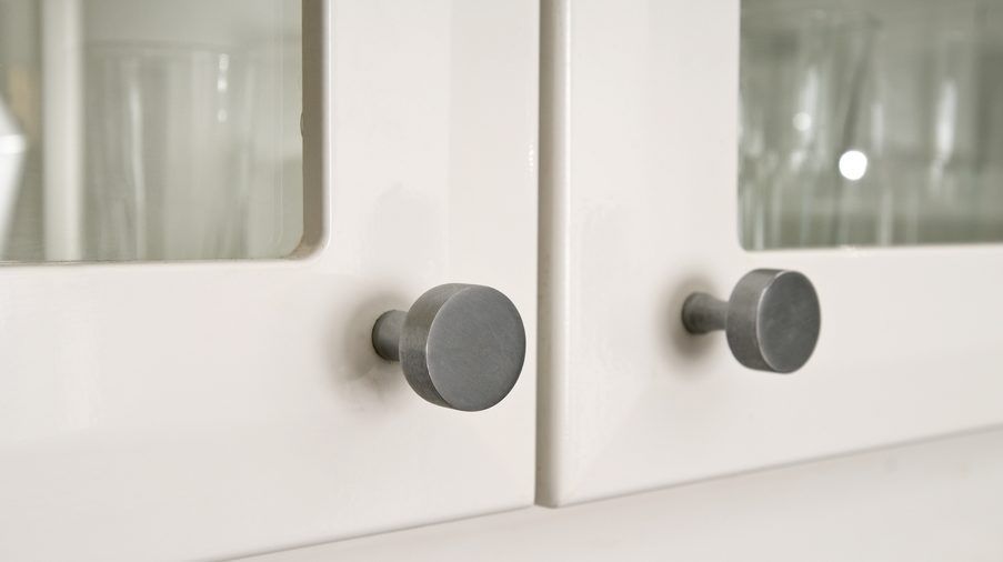 A close up of a kitchen cabinet with a glass door and two knobs.