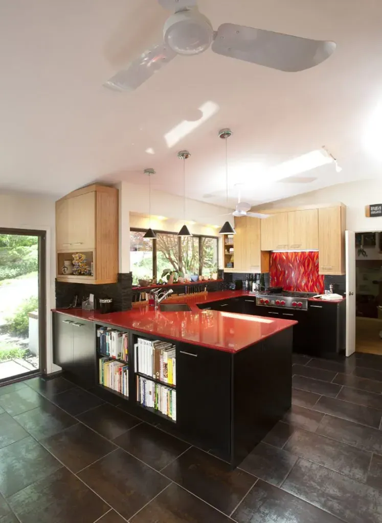 A kitchen with a red counter top and a ceiling fan