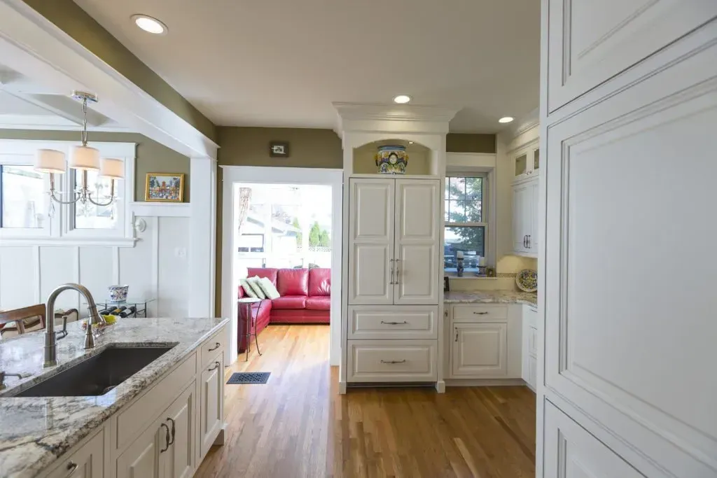 A kitchen with white cabinets , granite counter tops , a sink and a refrigerator.