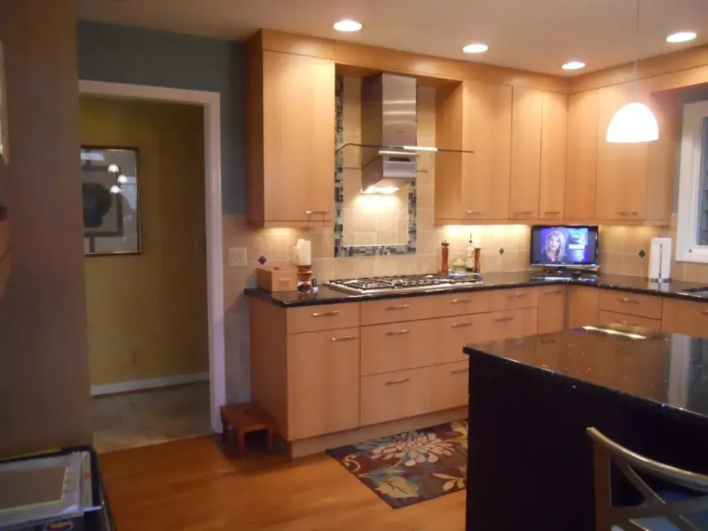 A kitchen with wooden cabinets and black counter tops