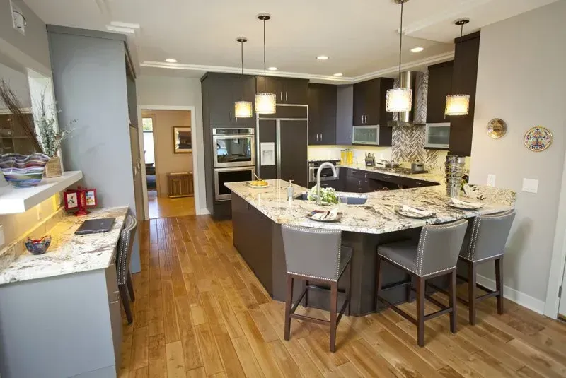 A kitchen with hardwood floors , granite counter tops , and stainless steel appliances.