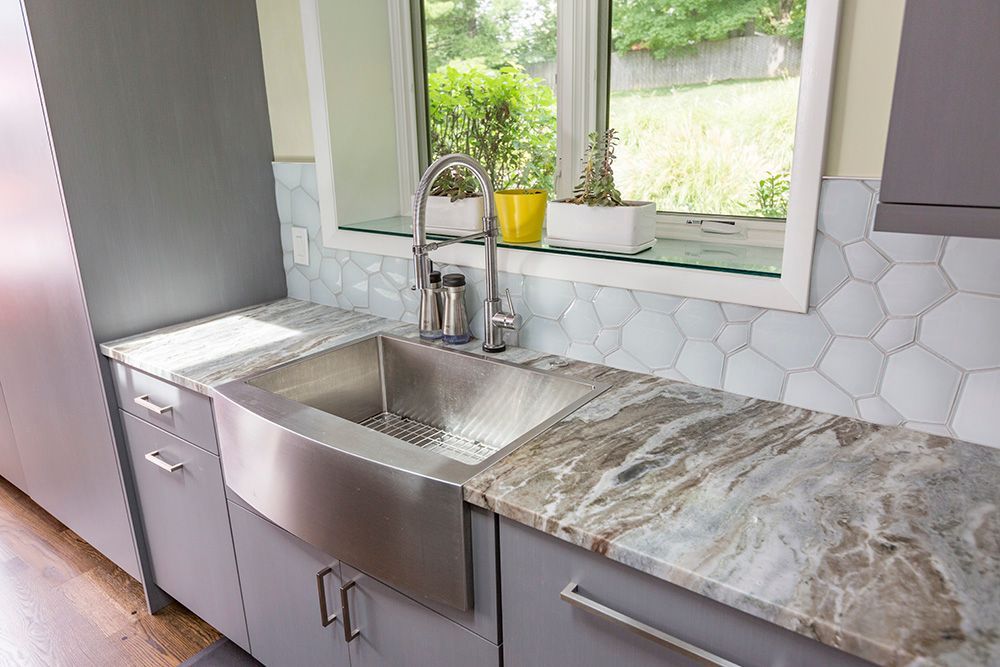 A kitchen with a stainless steel sink and granite counter tops.