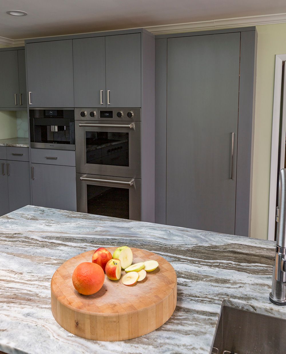A wooden cutting board with apples on it in a kitchen
