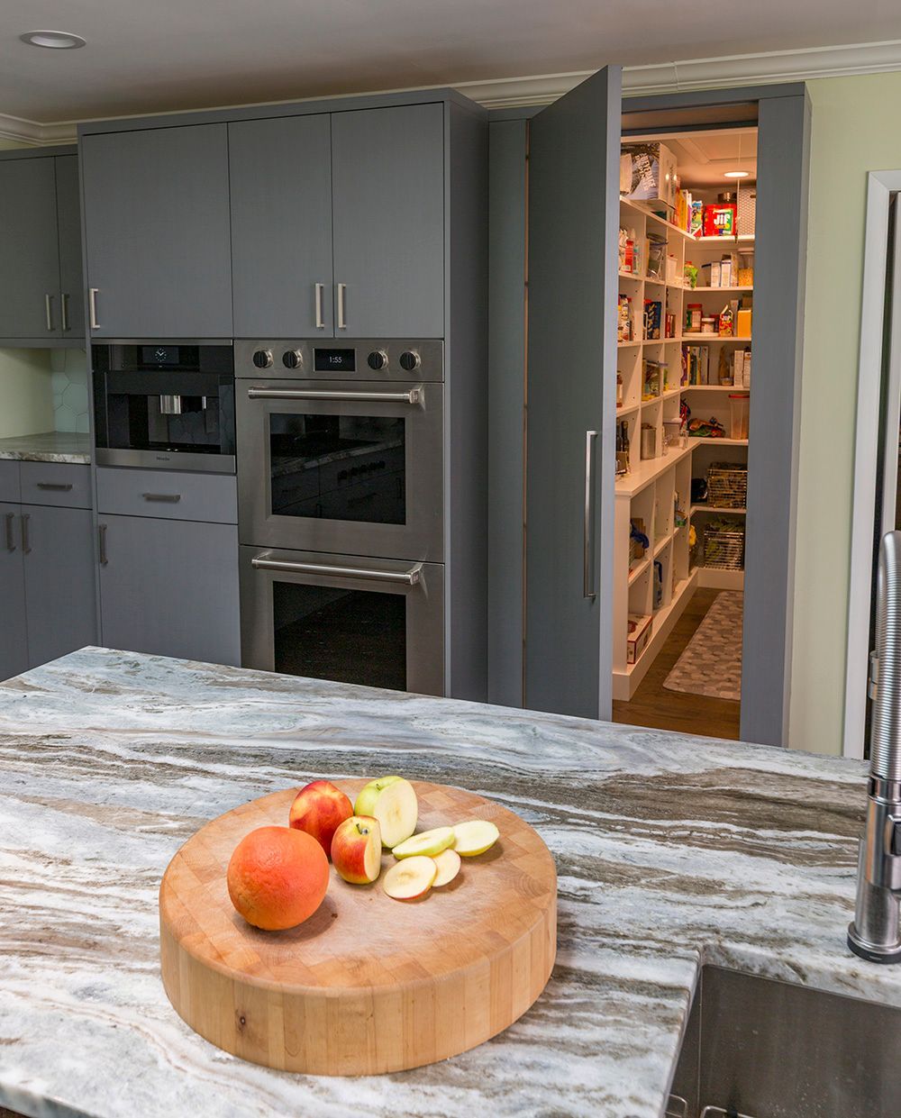 A kitchen with a wooden cutting board with apples on it