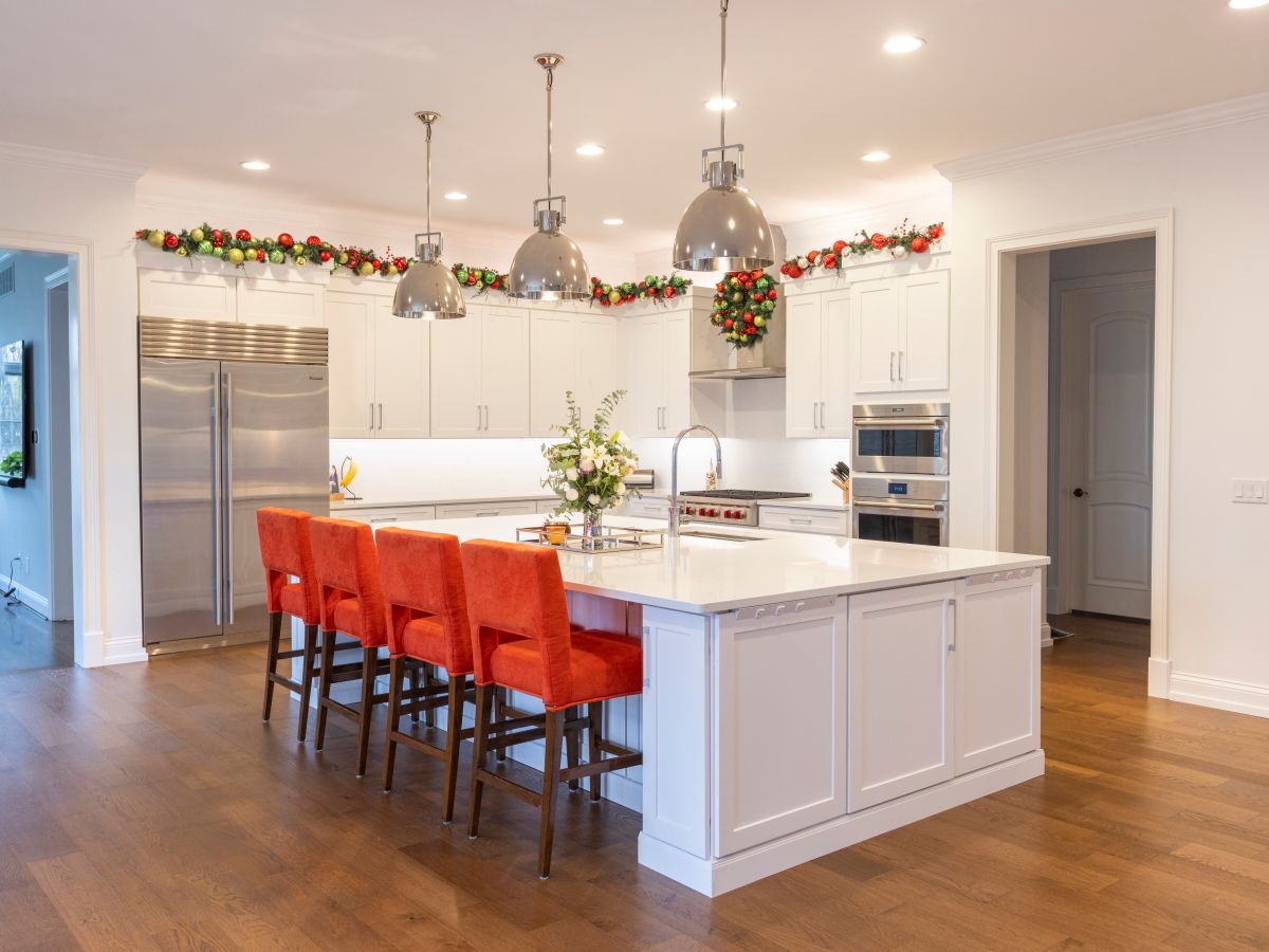 A kitchen with white cabinets and orange chairs and a large island.