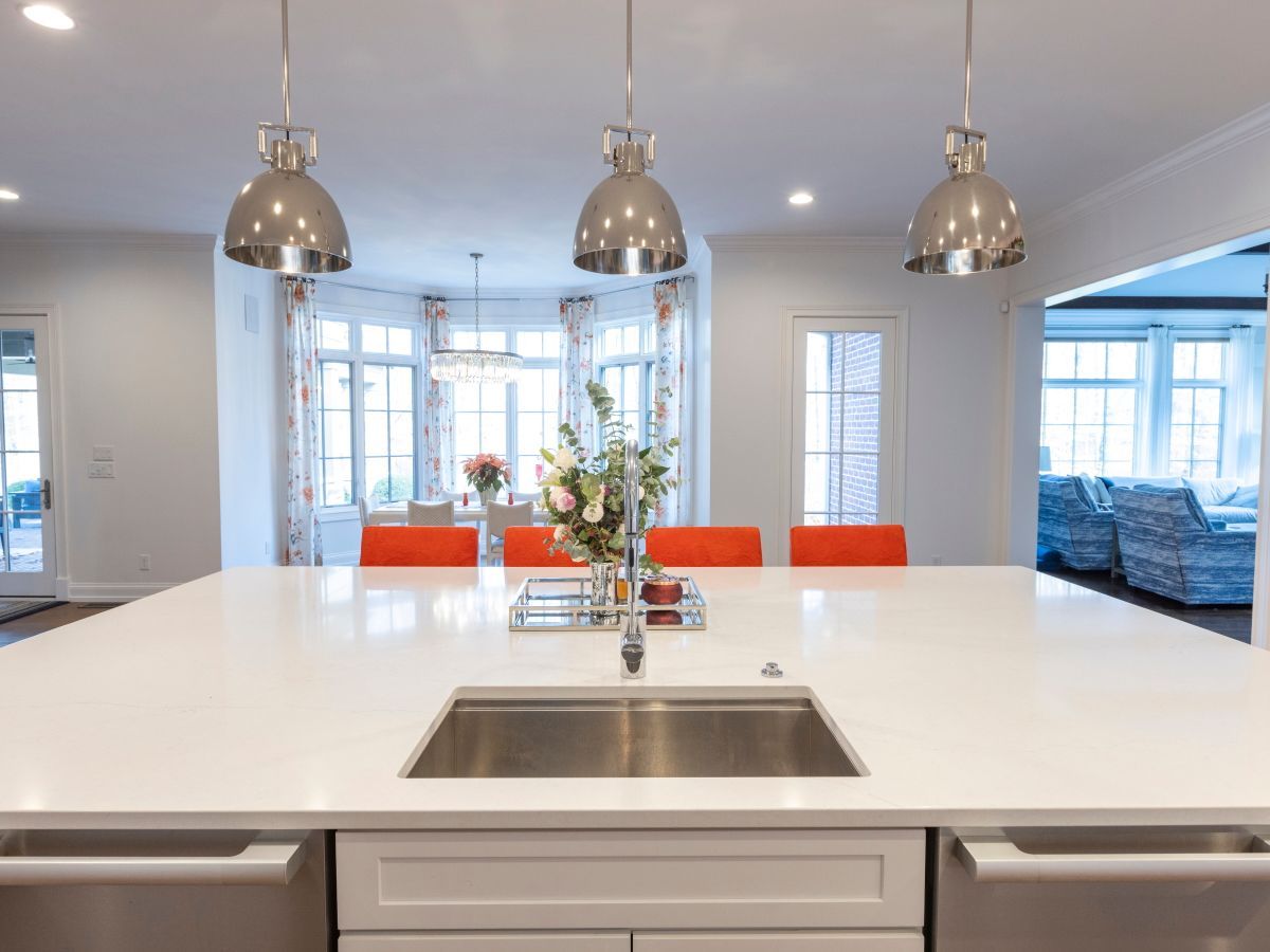 A kitchen with a stainless steel sink and white counter tops.