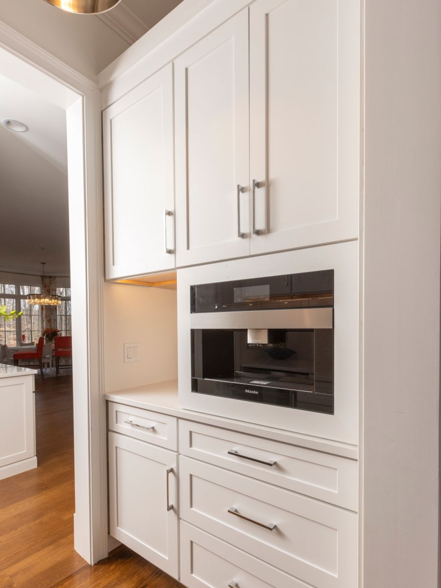 A kitchen with white cabinets and drawers and a microwave
