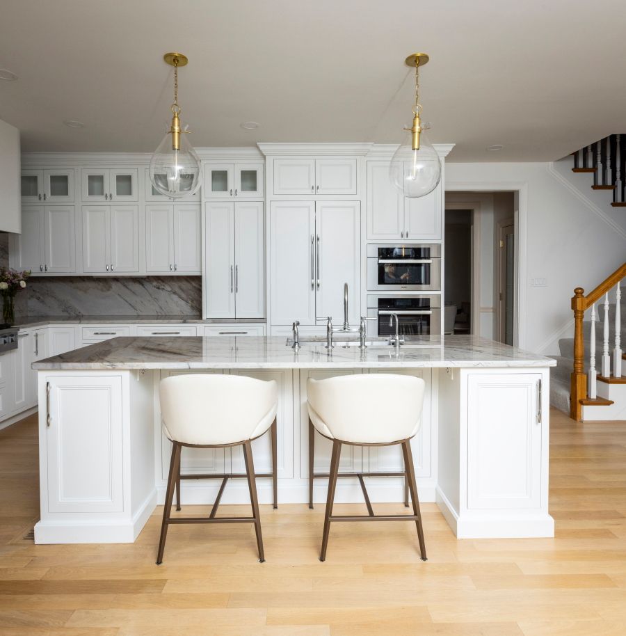A kitchen with white cabinets and marble counter tops