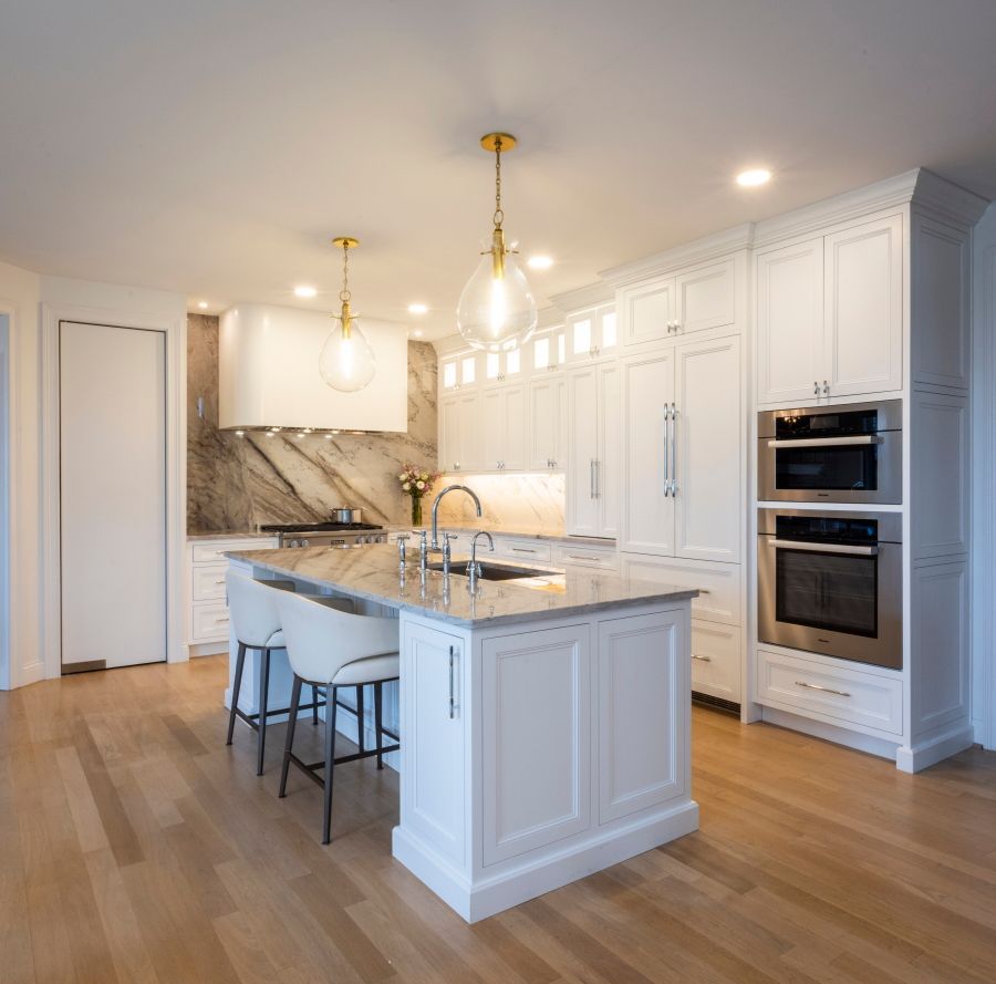 A kitchen with white cabinets , granite counter tops , and stainless steel appliances.