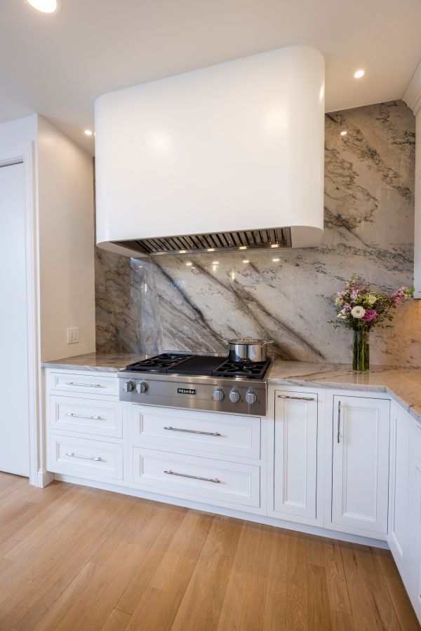 A kitchen with white cabinets and a stove top oven.