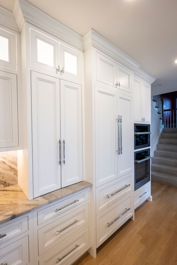 A kitchen with white cabinets , drawers , a refrigerator and an oven.