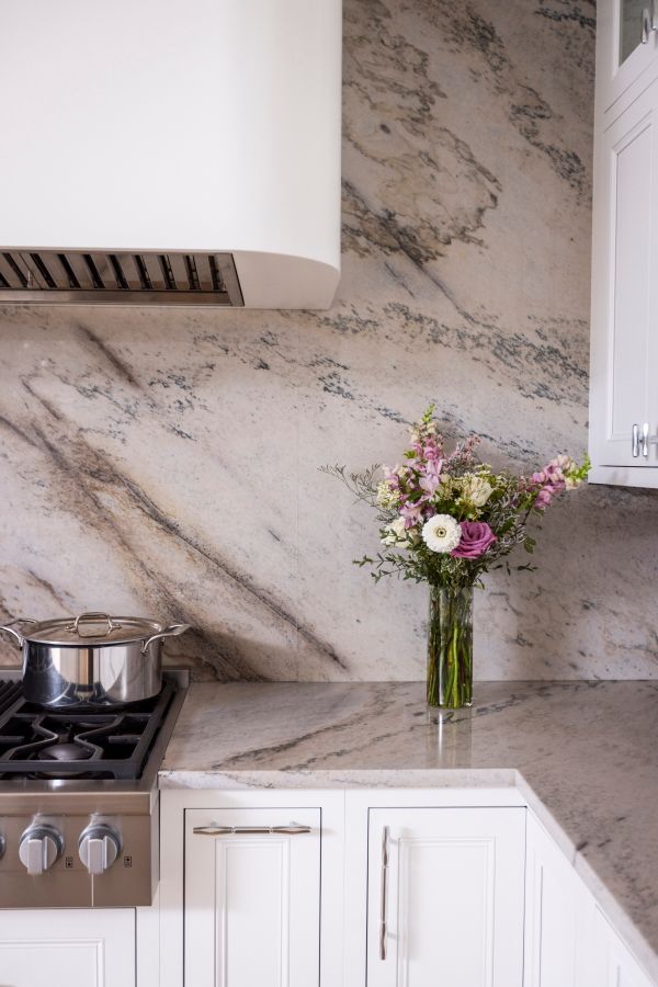 A kitchen with a pot on the stove and a vase of flowers on the counter.