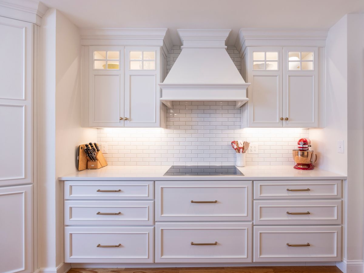 A kitchen with white cabinets and drawers and a stove top oven