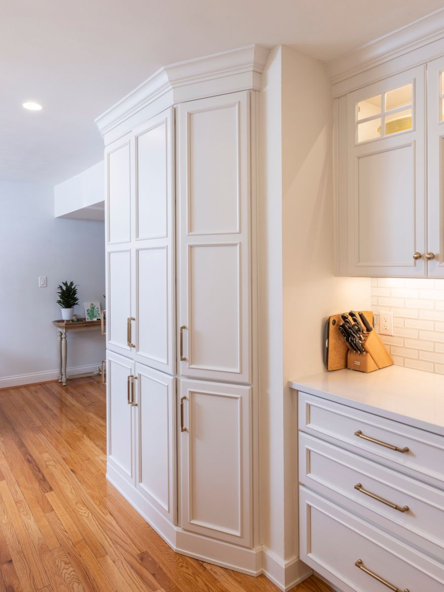 A kitchen with white cabinets and hardwood floors.
