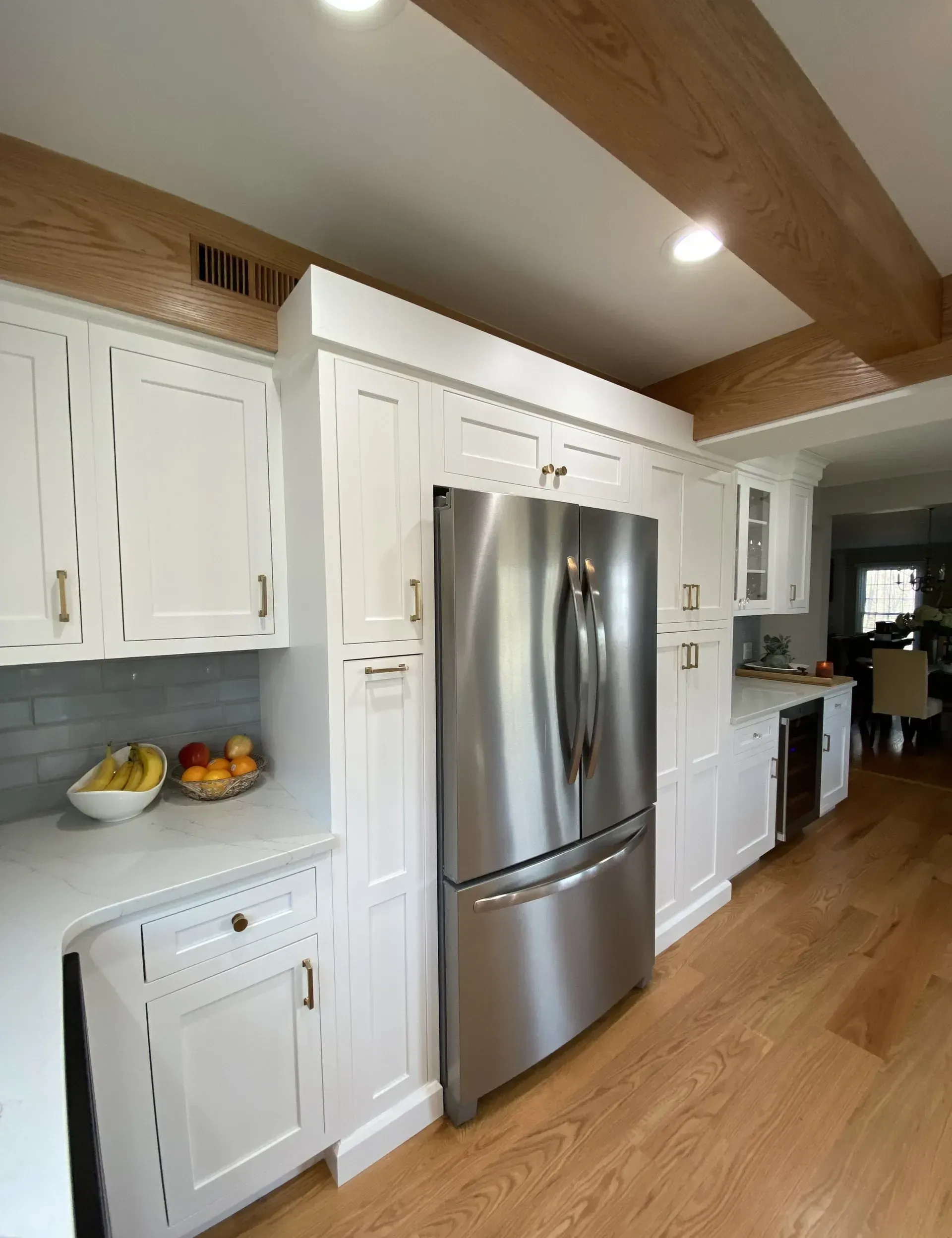 A kitchen with white cabinets and a stainless steel refrigerator