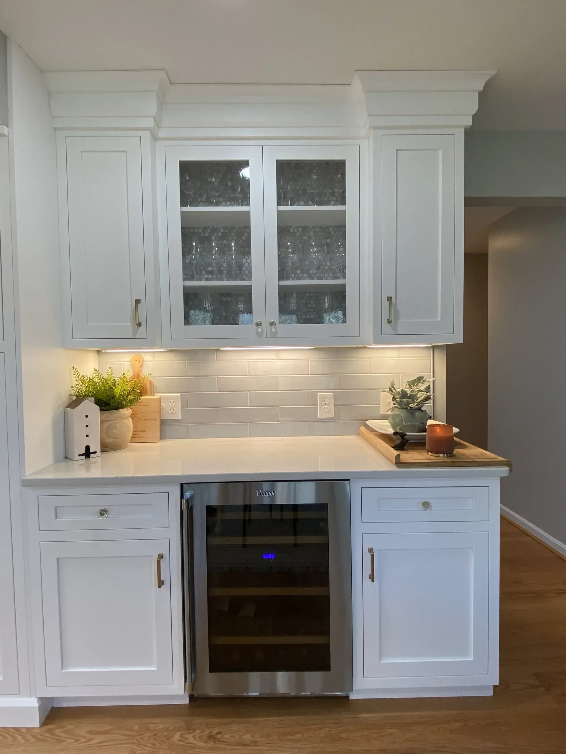 A kitchen with white cabinets and a wine cooler