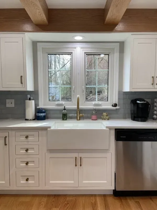 A kitchen with white cabinets , a sink and a window