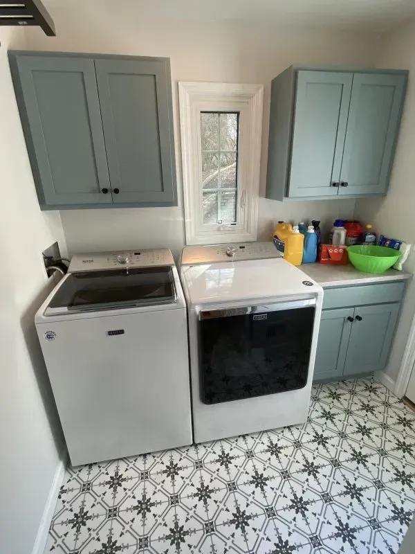 A laundry room with a washer and dryer and blue cabinets