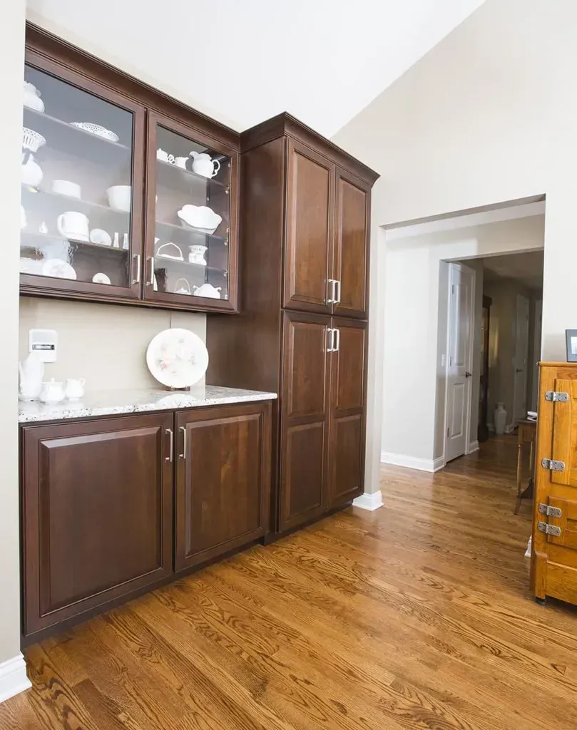 A kitchen with wooden cabinets and glass doors