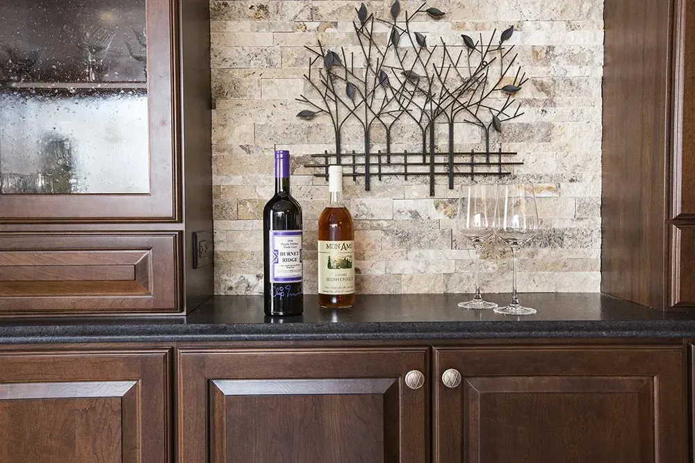 Two bottles of wine are on a counter in a kitchen