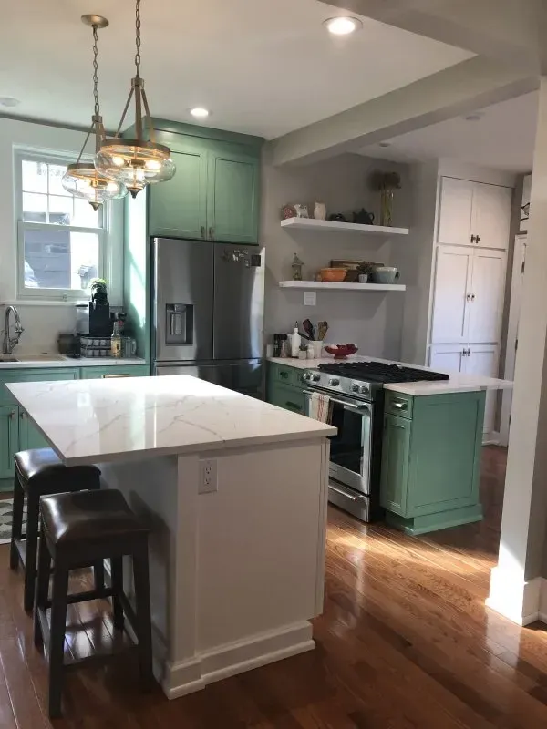 A kitchen with green cabinets and white counter tops