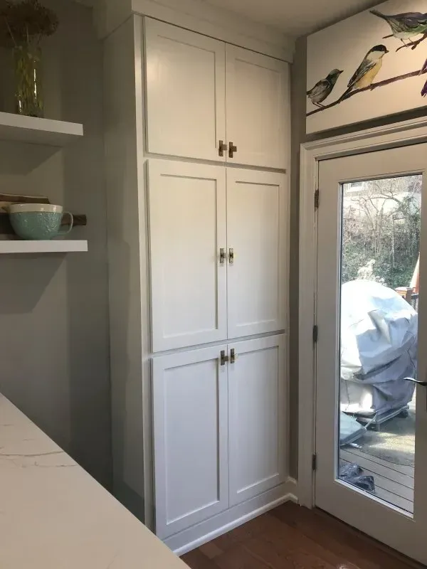 A kitchen with white cabinets and a glass door