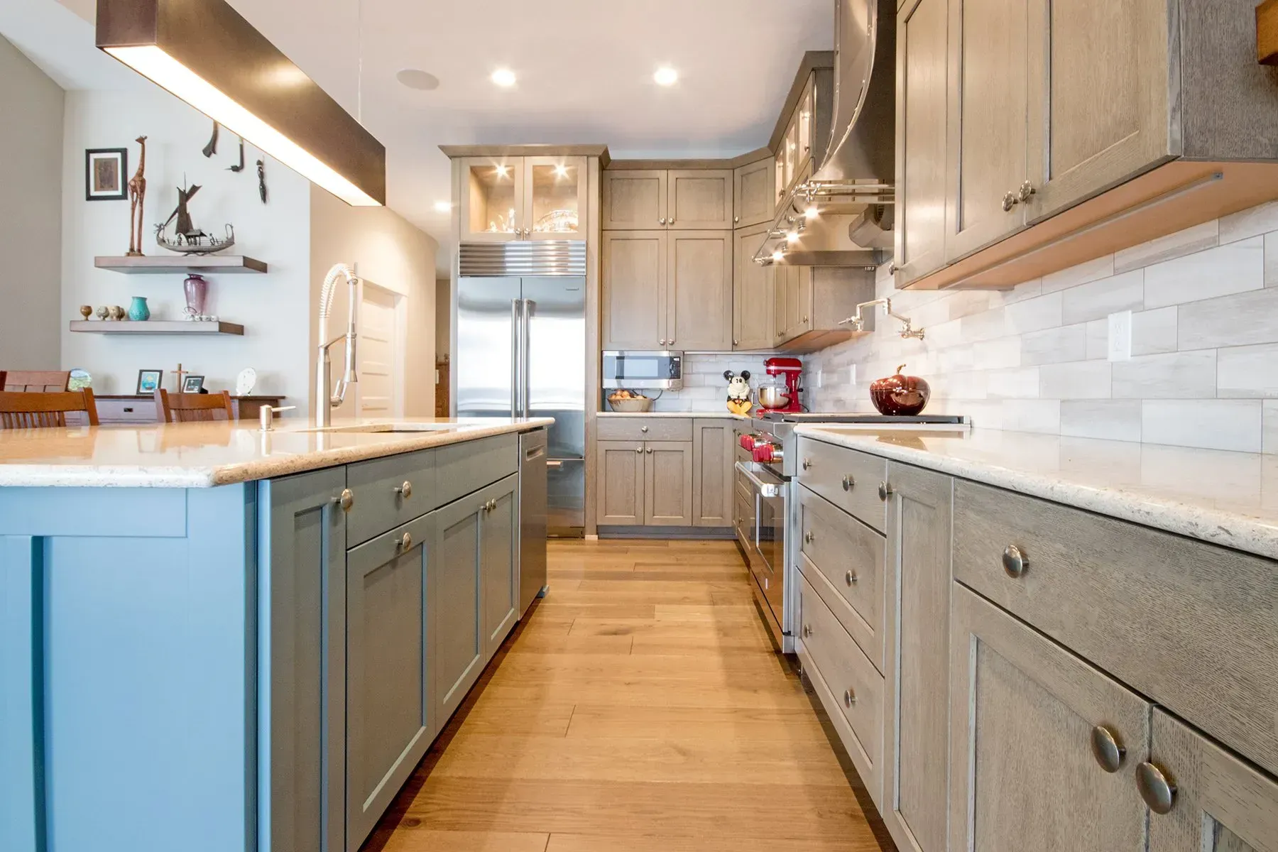 A kitchen with blue cabinets , white counter tops , and stainless steel appliances.