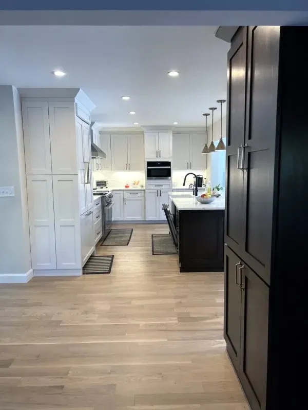 A kitchen with white cabinets and black cabinets and a large island.