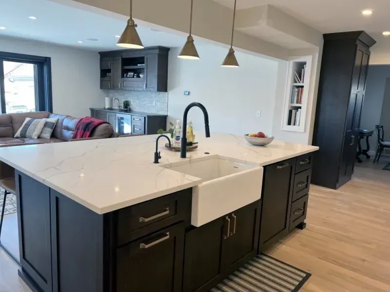 A kitchen with black cabinets and a white sink