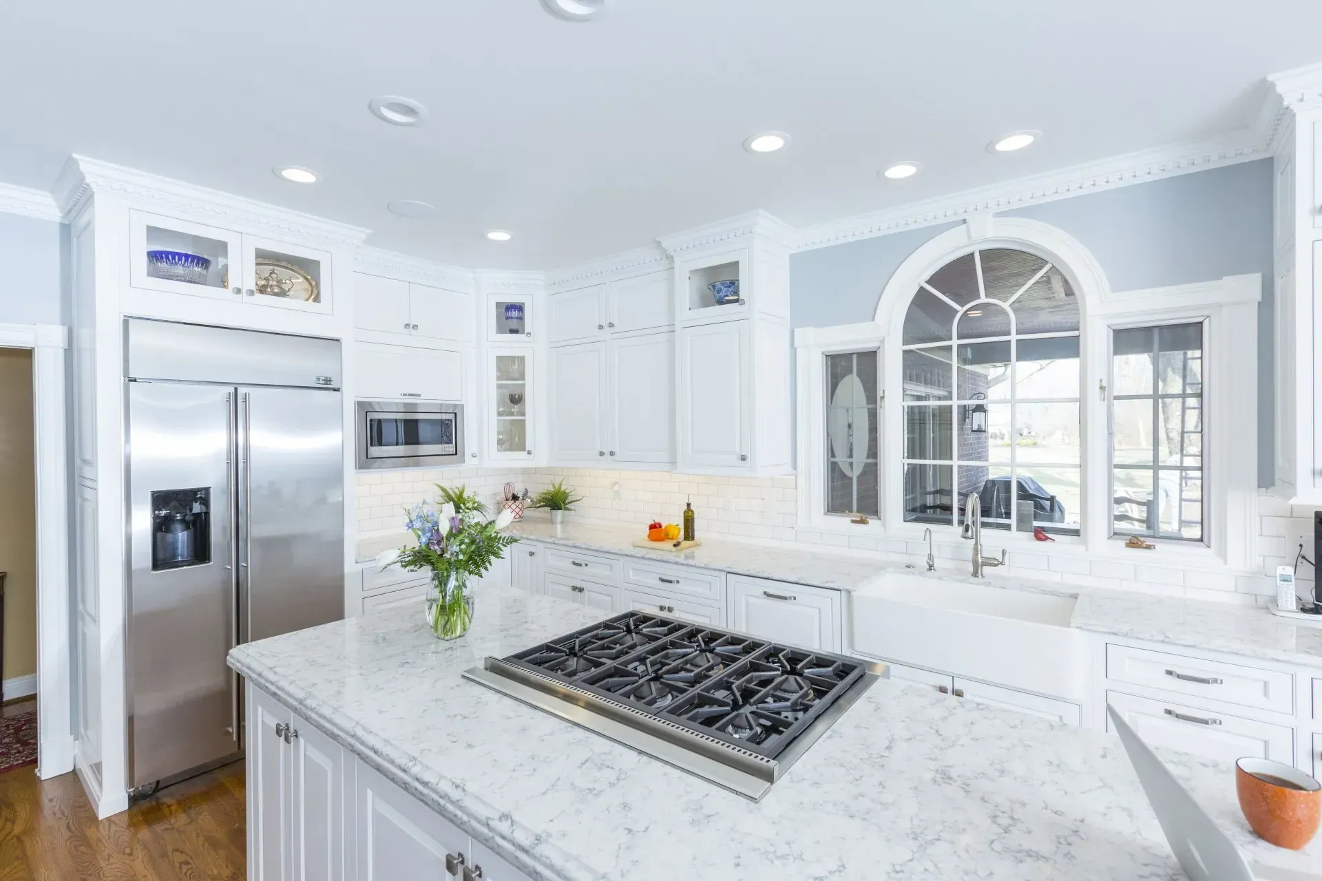 A kitchen with white cabinets , stainless steel appliances , a stove top oven and a refrigerator.