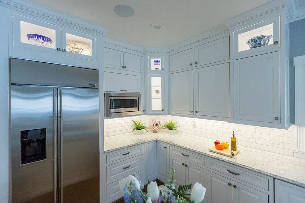 A kitchen with white cabinets , stainless steel appliances , a refrigerator and a microwave.