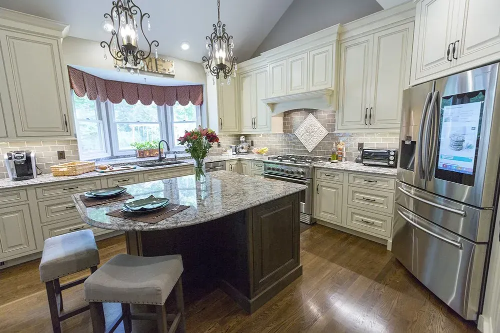 A kitchen with white cabinets , granite counter tops , stainless steel appliances and a large island.