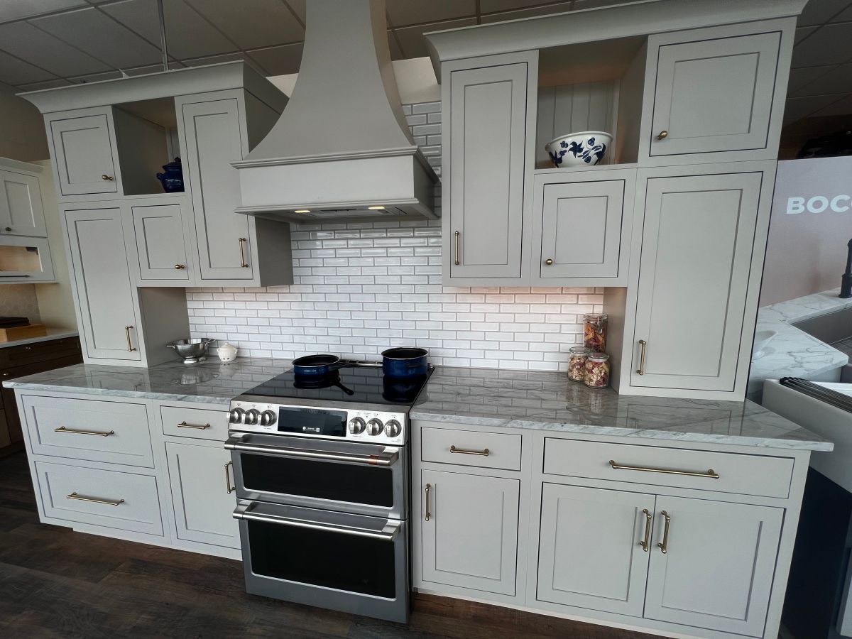 A kitchen with white cabinets , a stove , and a hood.