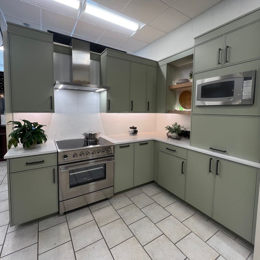 A kitchen with green cabinets and stainless steel appliances
