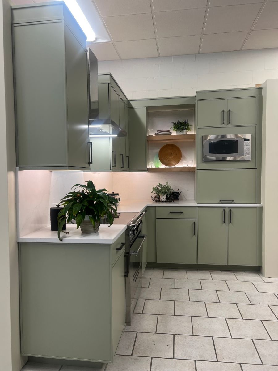 A kitchen with green cabinets and a plant on the counter