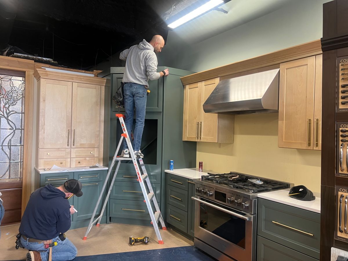 A man is standing on a ladder in a kitchen.