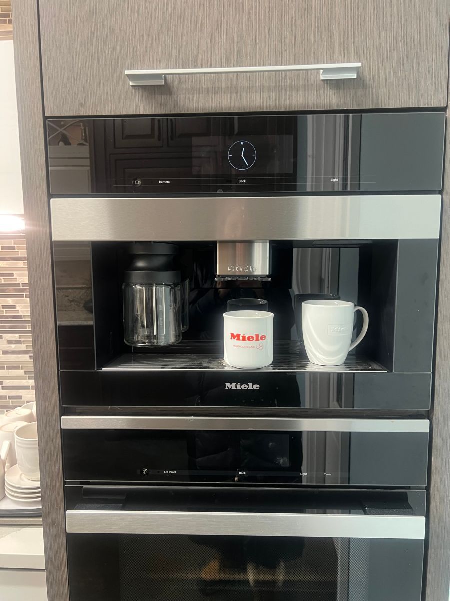 A kitchen with a coffee maker and two cups in it.