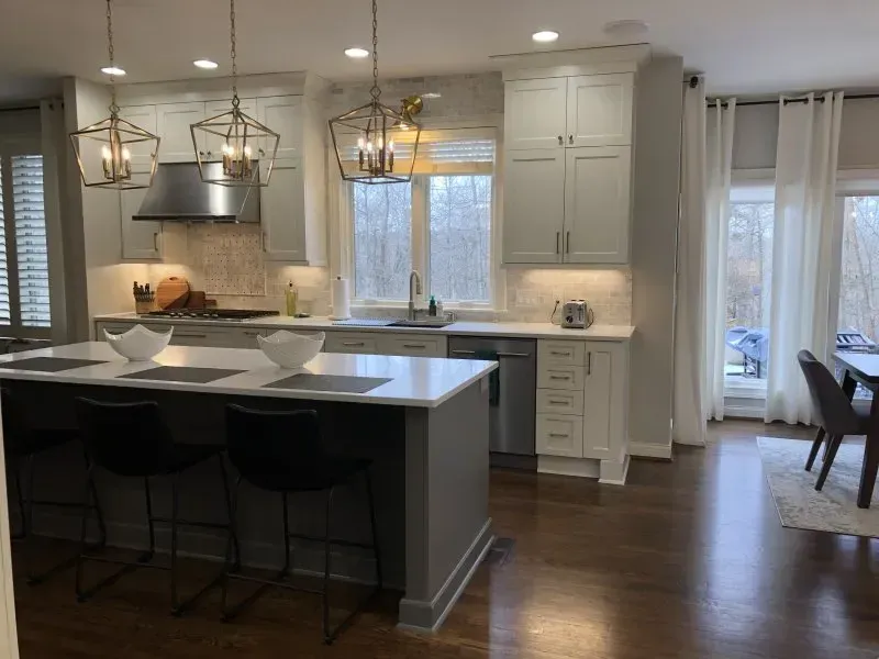 A kitchen with white cabinets and stainless steel appliances and a large island.