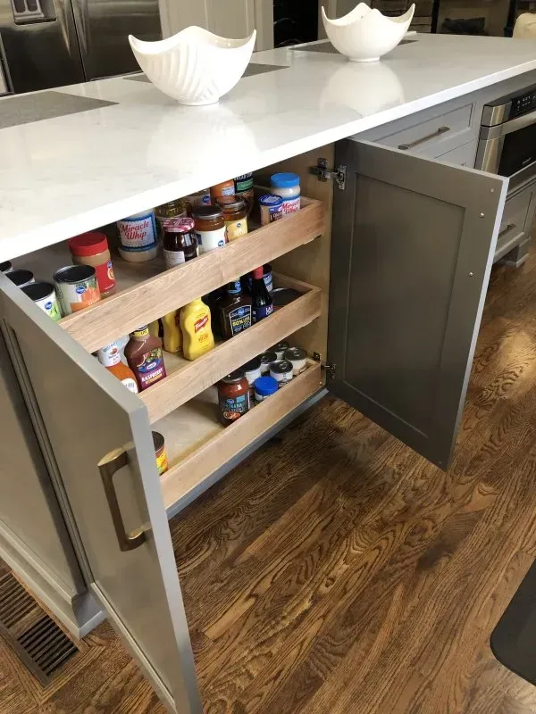 A kitchen island with a pull out pantry and a bowl on top of it.